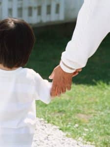 ヨチヨチ歩きの孫と庭先で手をつなぐ